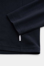 Close-up front-side view of the sleeve and hem of the 04651/ A trip in a bag Longsleeve-Poloshirt dark navy in soft cotton-cashmere piqué jersey with a small white woven label at the side seam.

<p>Dieses Longsleeve-Poloshirt von 04651/ A TRIP IN A BAG au