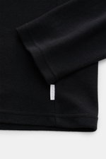 Close-up view of the sleeve and hem of the 04651/ A trip in a bag Longsleeve-Poloshirt schwarz, made of soft cotton-cashmere piqué jersey with a small web label in the side seam. 

<p>Dieses Longsleeve-Poloshirt von 04651/ A TRIP IN A BAG aus softem Piqué