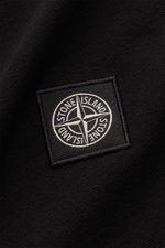 Close-up front view of the Stone Island Longsleeve-Poloshirt schwarz showing the tonal compass logo on black garment-dyed cotton piqué fabric with a grippy texture. Legere Kombinationen gelingen mit diesem klassischen Longsleeve-Poloshirt, das sich in stü