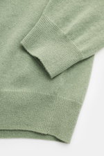Nahaufnahme des von Braun Cashmere Strickpolo salbei, fotografiert schräg von oben, zeigt feines Strickbild, elastisches Rippbündchen und weichen Griff.