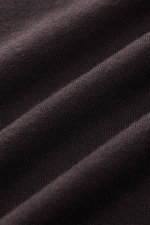 Nahaufnahme des dunkelbraunen von Braun Merino Strickpolo mit offenem Polokragen, feinem Merinowoll-Strickbild und weichem Griff.