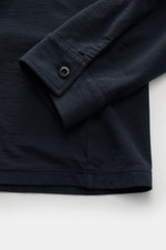 Nahaufnahme von Ärmel und Saum des Stone Island Longsleeve Jersey-Poloshirt 'Ghost Piece' navy aus leicht geflammtem Baumwolljersey, slim fit mit klassischer Sportmanschette und tonalem STONE ISLAND-Weblabel, fotografiert aus seitlicher Perspektive.