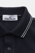 Close-up front view of Stone Island Long sleeve polo shirt dark navy collar with white stripes, fabric label, and branded button. <p>Create casual outfits that work with this classic long sleeve polo shirt in an understated sporty look in piece-dyed cotto