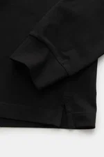 Close-up front view of the sleeve and hem of the Stone Island Long sleeve polo shirt black, showcasing its pure cotton jersey, robust piqué texture, elasticated fabric, garment-dyed finish, slim fit, polo collar with contrasting stripes, patch button plac