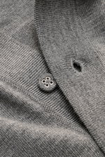 Nahaufnahme des Officine Générale Merino Strickpolo 'Bay' grau meliert, fotografiert aus schräger Perspektive, zeigt feines Strickbild, klassischen Polokragen, Rippbündchen und Knopfdetail aus reiner Merinowolle, Regular Fit, weicher Griff für souveräne E