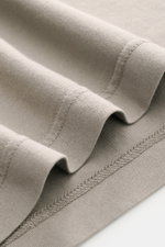 Nahaufnahme des taupefarbenen Fedeli Jersey Longsleeve-Poloshirts 'Zero' mit glattem, seidigem Griff, Jersey aus nachhaltiger Giza-Bio-Baumwolle, aufgenommen aus schräger Perspektive.