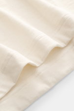 Close-up image of the cream fabric of the Fray Jersey longsleeve polo shirt 'Parigi' showing fine knit texture and stitching, photographed from above, featuring a mix of cotton and cashmere, soft feel, regular fit, classic polo collar, four-button placket