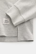 Close-up front view of Ami Paris Jersey longsleeve polo shirt grey melange showing cuff, hem, side slit, and logo patch in grey cotton jersey.

<p>Contemporary casualness: With its generous oversized fit, the long sleeve polo shirt from AMI PARIS becomes 