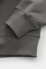 Nahaufnahme aus schräger Perspektive des grauen Maison Kitsuné Sweat-Troyer 'Chillax Fox' mit elastischen Rippbündchen, weichem Griff, Regular Fit, Troyer-Kragen mit Reißverschluss und Fuchs-Weblabel, gefertigt aus reiner Baumwolle.