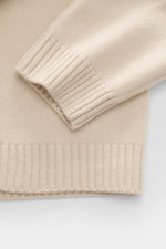 Nahaufnahme des Ärmelabschlusses des Maison Kitsuné Strickpolo sand aus reiner Wolle, weicher Griff, mittelfeines Strickbild, Rippbündchen.