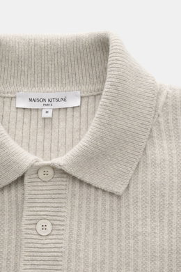 Nahaufnahme aus frontaler Perspektive des Maison Kitsuné Strickpolo 'Fox Head' sand aus reiner Wolle mit weichem Griff, breitem Rippstrick, mittelfeinem Strickbild, Regular Fit, gestricktem Polokragen, Drei-Knopf-Leiste, tonalem Fuchs-Stitching und komfor