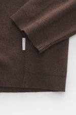 Nahaufnahme des Ärmels und Bunds des dunkelbraunen 04651/ A trip in a bag Longsleeve-Poloshirt 'Wool TP Polo LS' mit Jersey aus Baumwolle und Wolle, strukturiertem Griff, Regular Fit, klassischem Polokragen, Drei-Knopf-Leiste, kleinem Weblabel in der Seit