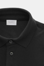 Nahaufnahme aus schräger Draufsicht des schwarzen 04651/ A trip in a bag Longsleeve-Poloshirt 'Wool TP Polo LS' mit Jersey aus Baumwolle und Wolle, strukturiertem Griff, Regular Fit, klassischem Polokragen, Drei-Knopf-Leiste, kleinem Weblabel in der Seite