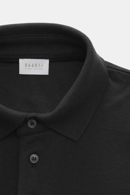 Nahaufnahme aus schräger Draufsicht des schwarzen 04651/ A trip in a bag Longsleeve-Poloshirt 'Wool TP Polo LS' mit Jersey aus Baumwolle und Wolle, strukturiertem Griff, Regular Fit, klassischem Polokragen, Drei-Knopf-Leiste, kleinem Weblabel in der Seite