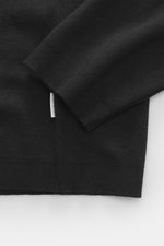 Nahaufnahme des Ärmels und Bunds des 04651/ A trip in a bag Longsleeve-Poloshirt 'Wool TP Polo LS' schwarz, Jersey aus Baumwolle und Wolle, strukturierter Griff, Regular Fit, klassischer Polokragen, Drei-Knopf-Leiste, kleines Weblabel in der Seitennaht, k