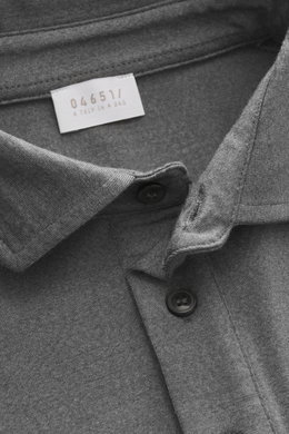Nahaufnahme aus schräger Draufsicht auf den Kragen und das Label des 04651/ A trip in a bag Longsleeve-Poloshirt 'WJ' grau meliert mit Mix aus Wolle und hochwertiger Microfaser, weichem Griff, Regular Fit, klassischem Polokragen und kurzen Saumschlitzen.