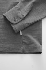 Nahaufnahme des Ärmels und Saums vom 04651/ A trip in a bag Longsleeve-Poloshirt 'WJ' grau meliert, Regular Fit, weicher Griff, Mix aus Wolle und Microfaser, klassischer Polokragen, kurze Saumschlitze.