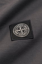 Nahaufnahme des dunkelgrauen Stone Island T-Shirts 'Basic Cotton' mit Weblabel auf der Brust, weiche reine Baumwolle, Slim Fit, Rundhalsausschnitt, Detail von schräger Perspektive.