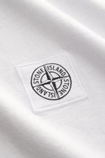 Stone Island T-Shirt 'Dyed Regular Fit' hellgrau aus reiner Baumwolle mit weichem Griff, Rundhalsausschnitt und Weblabel auf der Brust, Detailaufnahme.