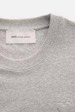 Close-up front view of the Ami Paris Rundhals-T-Shirt grau meliert showing the ribbed round neckline, soft grey melange cotton fabric, and subtle stitched heart logo, highlighting the heavy quality and soft touch. <p>Pardon my french - Mit diesem T-Shirt 