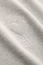 Close-up view of the Ami Paris Rundhals-T-Shirt grau meliert fabric showing the stitched heart logo on soft, heavy cotton jersey. <p>Pardon my french - Mit diesem T-Shirt von AMI PARIS kommen Sie bestimmt auch ohne gute Sprachkenntnisse durch, denn das ab