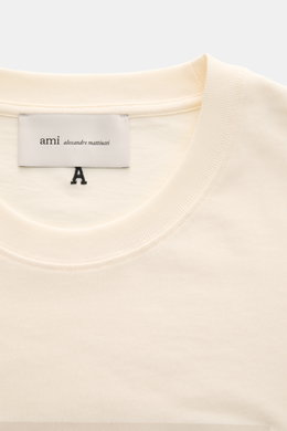 Ami Paris Rundhals-T-Shirt creme aus reiner Baumwolle mit weichem Griff, Regular Fit, Rundhalsausschnitt, geflocktem AMI PARIS-Schriftzug, Detailansicht von oben.