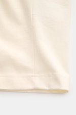 Ami Paris Rundhals-T-Shirt creme, Detailaufnahme vom Saum, Jersey aus reiner Baumwolle, weicher Griff, Regular Fit, geflockter Schriftzug vorne, Logo-Stitching hinten.
