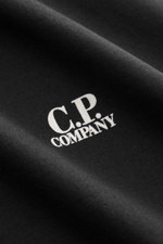 Nahaufnahme des schwarzen C.P. Company Rundhals-T-Shirts mit weißem Logo-Print auf der Brust, weicher Baumwoll-Jersey.