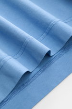 Nahaufnahme des B.F. Knitwear Rundhals-T-Shirts rauchblau von unten, reine Baumwolle, weicher Griff, Slim Fit, Rundhalsausschnitt, kurze Saumschlitze.