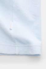 Close-up bottom hem view of 04651/ A trip in a bag Terry T-shirt 'Terry Tee' pastel blue made of soft pure cotton terrycloth with a small woven label in the side seam. The clean T-shirt 'Terry Tee' by 04651/ A TRIP IN A BAG is made of soft terry in pure c