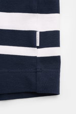 Nahaufnahme des Details eines 04651/ A trip in a bag Rundhals-T-Shirts "Nunu" navy/weiß gestreift mit kleinem Weblabel, schwerer Baumwollqualität, weichem Griff und Regular Fit, fotografiert frontal auf weißem Hintergrund.