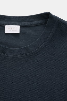 Close-up front view of the navy 04651/ A trip in a bag Piqué T-shirt showing the crew neck, woven label, and textured piqué cotton fabric.

<p>Summer essential: This piqué T-shirt from 04651/ A TRIP IN A BAG is a versatile staple that's perfect for warm d
