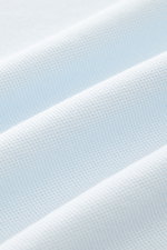 Close-up of pastel blue fabric texture showing fine piqué knit with soft folds, photographed from a macro perspective. The 04651/ A trip in a bag Piqué T-shirt pastel blue is a summer essential: This piqué T-shirt from 04651/ A TRIP IN A BAG is a versatil