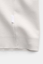 Nahaufnahme des hellgrauen 04651/ A trip in a bag Piqué-T-Shirts 'TP' mit sichtbarem Weblabel an der Seitennaht, Piqué-Struktur und Rippbündchen, Slim Fit, Rundhalsausschnitt, aus reiner Baumwolle mit kernigem Griff, fotografiert aus schräger Perspektive.