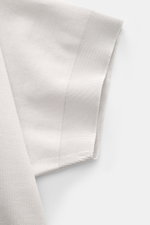 Nahaufnahme des Ärmels von 04651/ A trip in a bag Piqué-T-Shirt 'TP' hellgrau aus reiner Baumwolle, Slim Fit, mit Rundhalsausschnitt, Weblabel, Rippbündchen, kerniger Griff, von oben fotografiert.