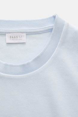 Frontnahes Detailfoto des pastellblauen 04651/ A trip in a bag Piqué-T-Shirts 'TP' mit Rundhalsausschnitt, Weblabel und Rippbündchen.