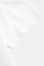 Close-up top-down view of the cuff and fabric texture of the 04651/ A trip in a bag Piqué-T-Shirt 'TP' weiß, a slim fit white cotton piqué t-shirt with a round neckline.

<p>Summer Essential: Das Piqué-T-Shirt von 04651/ A TRIP IN A BAG überzeugt an warme