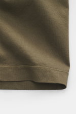 Close-up view of the hem and fabric texture of the Stone Island Crew neck T-Shirt 'Stellina' brown, showcasing pure cotton jersey, soft feel, slim fit, crew neckline, and subtle Stellina stitching with distinctive overlock seams.