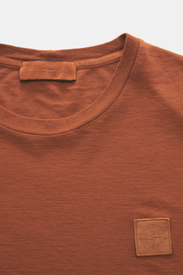Close-up front view of Stone Island Crew Neck T-Shirt 'Ghost Piece' rust brown showing crew neckline and tonal woven label.

<p>With this crew neck T-shirt made of smooth cotton jersey, featuring a tonal woven label on the chest, STONE ISLAND offers a com