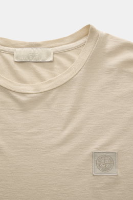 Stone Island Crew Neck T-Shirt 'Ghost Piece' beige shown from front close-up, smooth cotton jersey with tonal woven label on chest.  
<p>With the crew neck T-shirt made of smooth cotton jersey, featuring a tonal woven label on the chest, STONE ISLAND deli