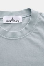 Close-up front view of Stone Island Crew Neck T-Shirt 'Organic Cotton' smoky blue showing crew neckline and woven label on the chest.

Description: 
<p>Timeless, versatile, and sustainable: The STONE ISLAND t-shirt impresses as a modern casual essential. 