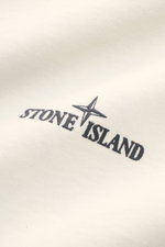 Close-up front view of Stone Island Rundhals-T-Shirt 'Printed Tee' creme showing soft organic cotton fabric with black logo and compass print.

<p>Lässiger Komfort trifft auf ikonisches Design: Mit diesem T-Shirt aus Bio-Baumwolle präsentiert <span class=