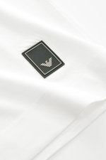 Nahaufnahme des Emporio Armani Rundhals-T-Shirts offwhite mit Logo-Detail auf der Brust, weicher Griff, Jersey aus Lyocell und Baumwolle, Slim Fit, fotografiert von oben.