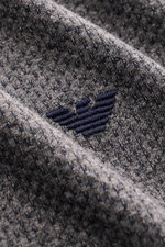 Nahaufnahme aus schräger Perspektive des Emporio Armani Rundhals-T-Shirts dunkelgrau meliert mit Jersey aus Baumwolle und Microfaser, leicht griffiger Struktur und Logo-Stitching auf der Brust, Regular Fit, puristische Eleganz für jeden Tag.