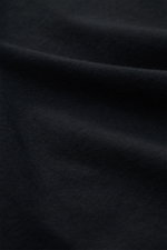 Nahaufnahme des schwarzen Officine Générale Rundhals-T-Shirts 'Cneck Tee' aus weichem Jersey reiner Bio-Baumwolle mit Slim Fit, fotografiert aus seitlicher Perspektive.