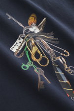 Nahaufnahme aus schräger Perspektive des Barbour Rundhals-T-Shirts navy mit lässigem Schlüsselbund-Print auf der Brust, weiche reine Baumwolle, Regular Fit, rückwärtiges Weblabel.