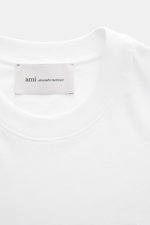 Ami Paris Crew Neck T-Shirt white shown from a close-up top-front view, featuring a pure cotton jersey, soft touch, slim fit, crew neckline, heart stitching on chest, and tonal AMI stitching on back. Classic jersey basic by the French label AMI PARIS: Thi