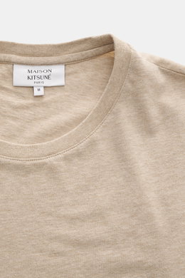 Close-up front view of Maison Kitsuné Crew Neck T-Shirt 'Fox Head' beige melange showing soft cotton jersey and ribbed crew neckline.

<p>Sporty essential from MAISON KITSUNÉ: With the typical fox patch on the chest, this shirt will be a favorite piece in
