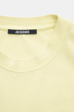 Nahaufnahme des hellgelben Jacquemus Rundhals-T-Shirts, Slim Fit mit weichem Griff, reine Baumwolle, Grosgrain mit Logo-Stitching, von oben fotografiert.