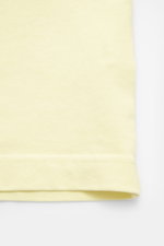 Close-up view of the Jacquemus Crew Neck T-Shirt light yellow hem, showing pure cotton fabric with soft touch, slim fit, and grosgrain with logo stitching on chest.